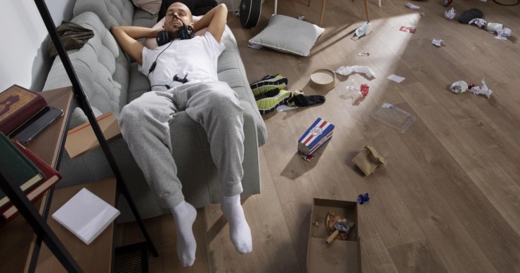 uomo appisolato in un appartamento disordinato