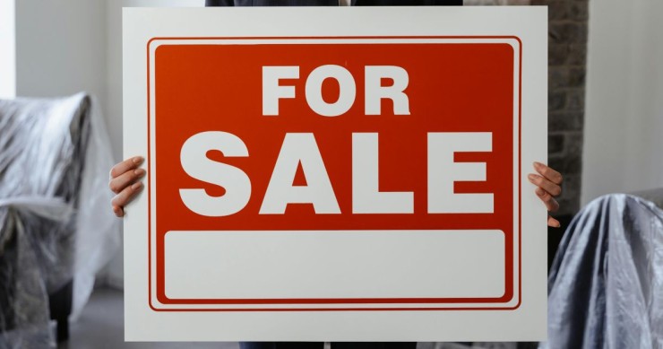 donna che sorregge cartello vendesi