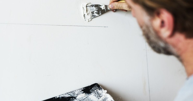 operaio che applica lo stucco con una spatola