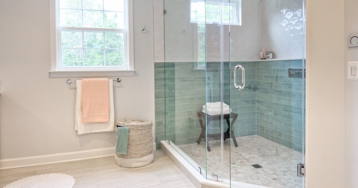 Una doccia a pavimento con piastrelle verdi e box di vetro trasparente