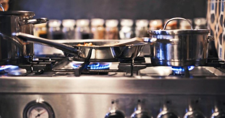 Una cucina a gas cromata con I fornelli perfettamente accesi
