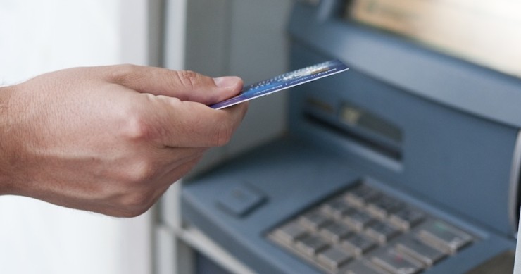 Mano che inserisce bancomat per prelevare