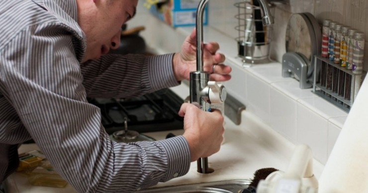 Un idrauluco lavora sul rubinetto della cucina