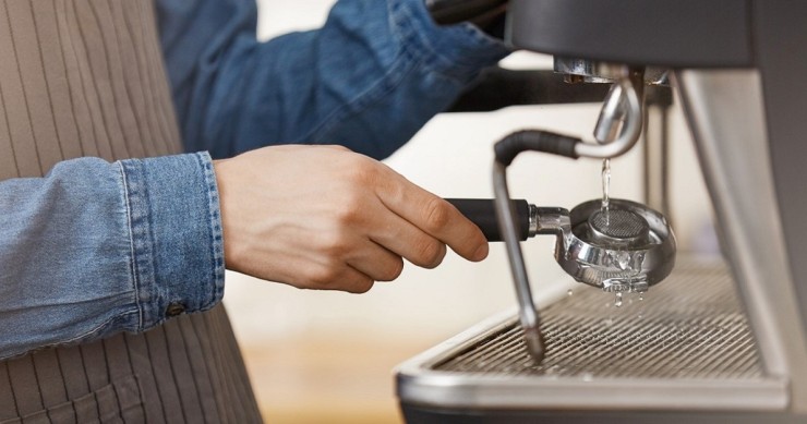 Un barista esegue la pulizia della macchina del caffè