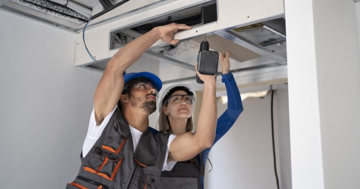 Due tecnici alle prese con l'installazione di un condizionatore