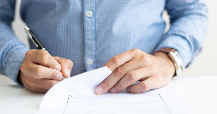Primo piano di un uomo che firma un documento