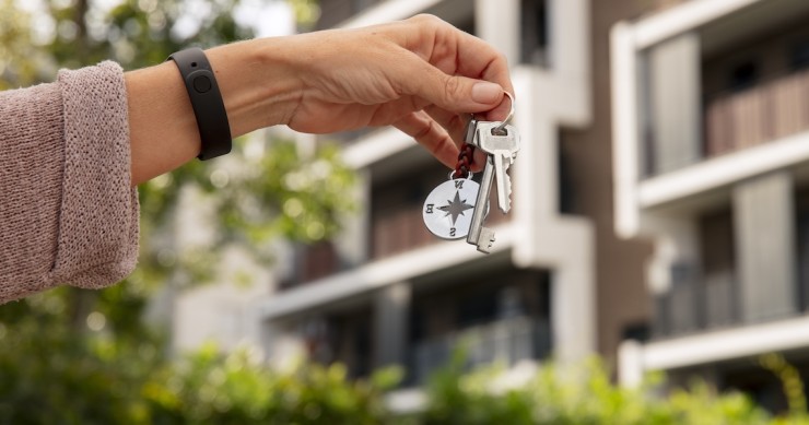 Mazzo di chiavi in primo piano ed esterno residenziale sullo sfondo