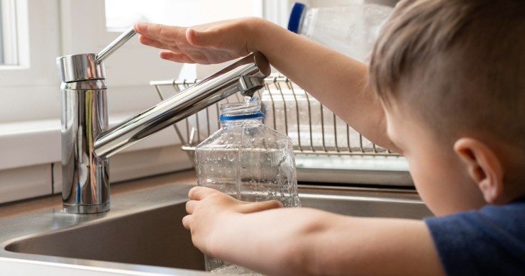 Un bambino raccoglie acqua dal rubinetto