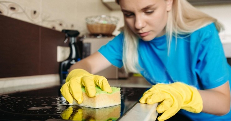 Una donna passa una spugna sul piano a induzione