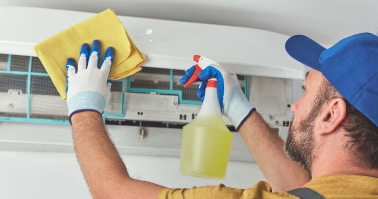 Tecnico in guanti gialli pulisce il condizionatore