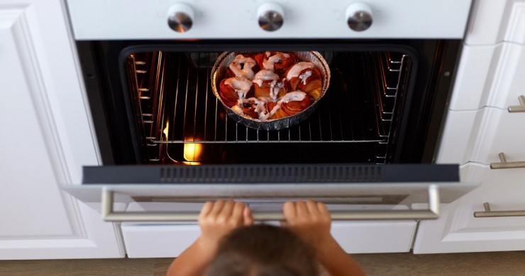 Bambina apre un forno con un dessert dentro