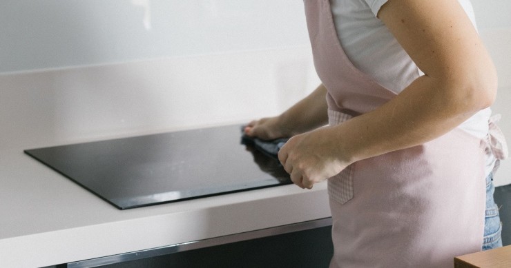 Donna pulisce un piano a induzione