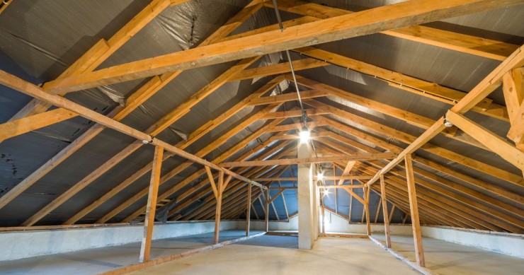 Sottotetto vuoto con travi in ​​legno a vista e tetto spiovente, pulito e luminoso, pronto per la ristrutturazione