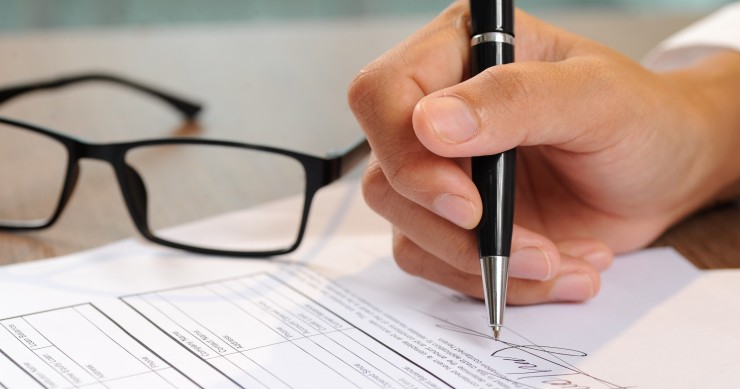 Primo piano di una mano che firma un documento 