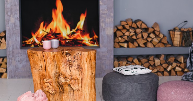 Interno in stile scandinavo con camino, tavolino ricavato da un ceppo e catasta di legna
