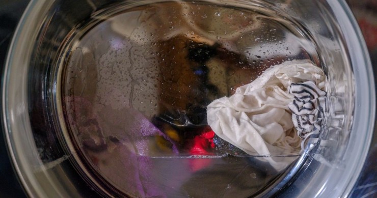 Lavatrice con bucato e acqua nel cestello