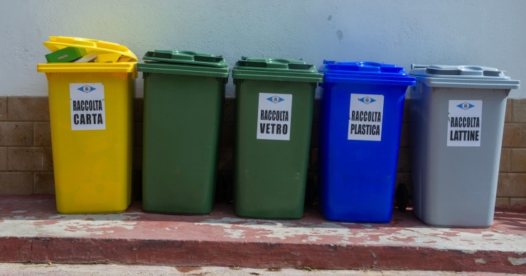 Cinque bidoni di riciclaggio colorati organizzati per la segregazione dei rifiuti in un contesto urbano