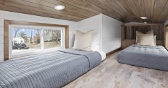 El dormitorio secundario está situado en un altillo accesible, ofreciendo un espacio íntimo con capacidad para dos camas individuales.