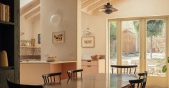 La cucina è completata da mobili e piani di lavoro in delicate tonalità rosa, superfici in acciaio inossidabile e un paraschizzi in terrazzo che introduce texture e sfumature