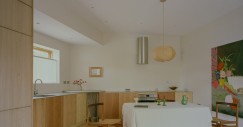 La cucina combina legno di pino, quercia e ciliegio con superfici in acciaio inossidabile e un bancone in cemento nell'angolo