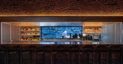 Sulla parete del bar, un'opera digitale e interattiva dell'autore Ian Cheng domina la scena visiva