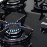 Una cucina a gas nera con un fuoco acceso