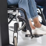 Piedi di donna disabile, sedia a rotelle, pavimento bianco