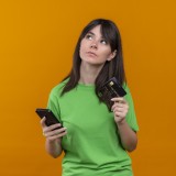 Giovane ragazza tiene in mano un telefono e una carta di credito