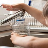 Un bambino raccoglie acqua dal rubinetto