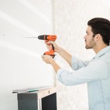 Un uomo pratica un foro su una parete