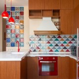 Cucina marrone con particolari rossi come il frigorofero e le lampade