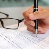 Primo piano di una mano che firma un documento