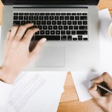 Vista dall'alto di una postazione di lavoro con laptop e appunti