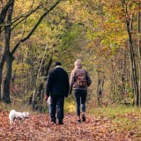 Una coppia con un cane bianco passeggia nel bosco