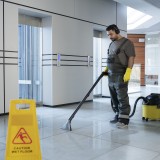 Un operatore delle pulizie che lava l’androne di un palazzo