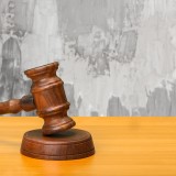 Martelletto di legno con sfondo di parete rovinata che illustra visivamente il classico caso di perizia per danni da infiltrazioni