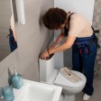 Un idraulico lavora alla cassetta di un WC