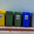 Cinque bidoni di riciclaggio colorati organizzati per la segregazione dei rifiuti in un contesto urbano