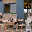Una donna che si rilassa fuori dalla sua moderna tiny house mobile in un ambiente naturale panoramico.